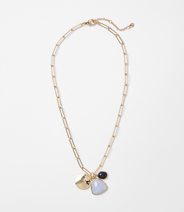 A gold chain necklace with three charms hangs against a plain white background.