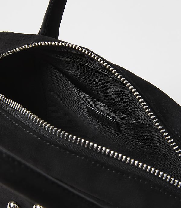 A black suede handbag with a silver zipper is shown against a plain white background.