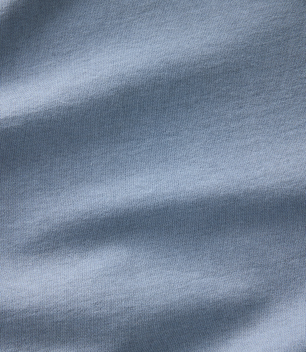 Soft, light blue fabric with gentle folds and shadows fills the frame.