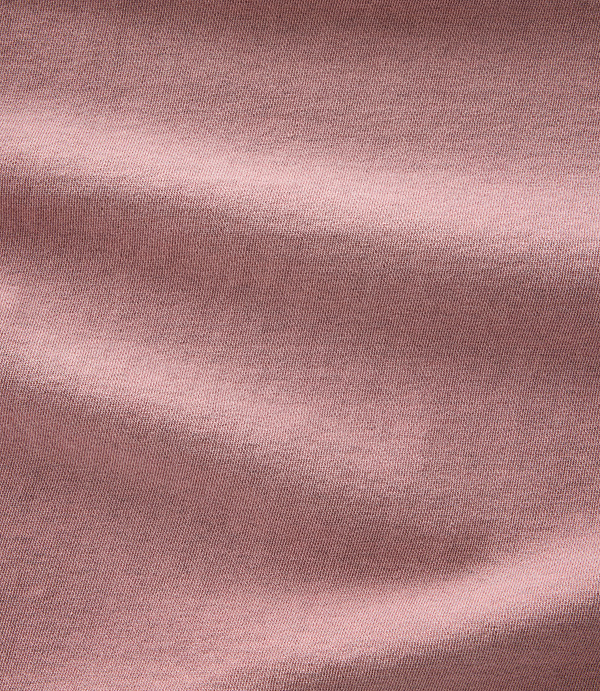 Soft, dusty rose fabric with gentle folds and shadows fills the frame.