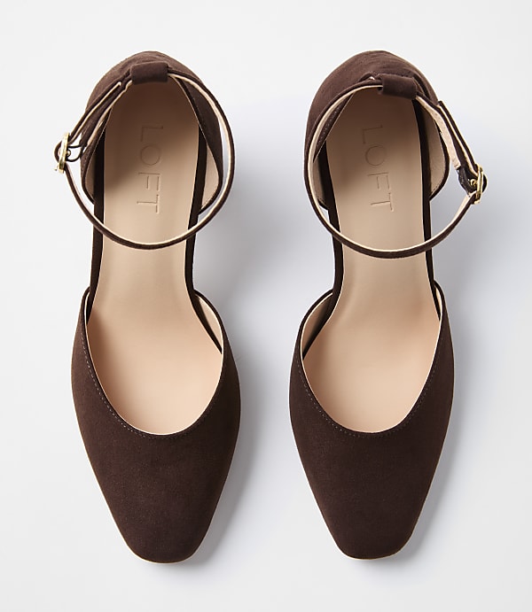 A pair of brown suede ankle strap flats with pointed toes are laid out on a white background.