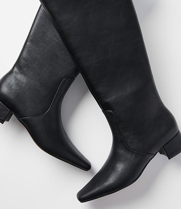 A pair of black leather knee-high boots with a square toe and low heel rests on a plain white background.