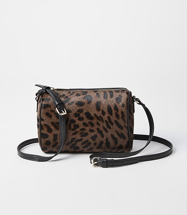 A leopard-print crossbody bag with black leather accents rests on a plain white background.