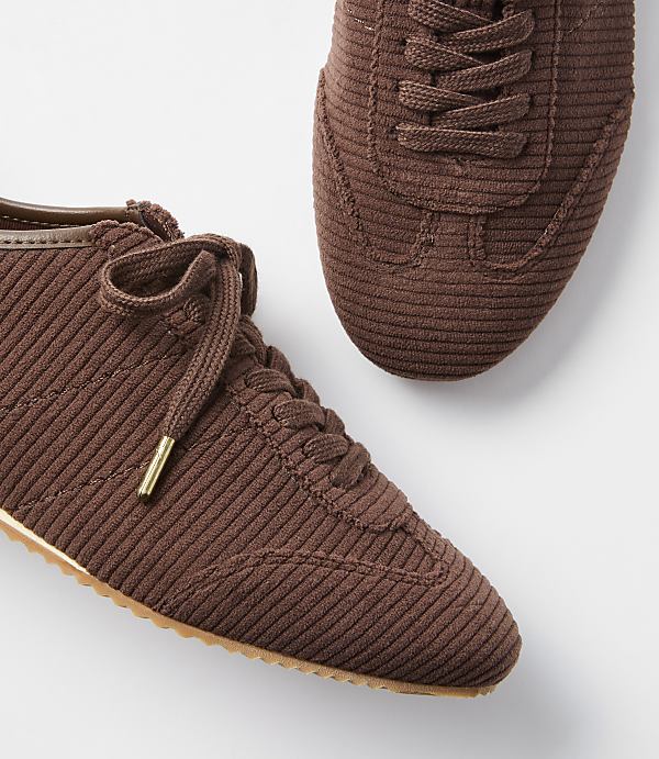 Two brown corduroy sneakers with white laces are laid out on a white background.