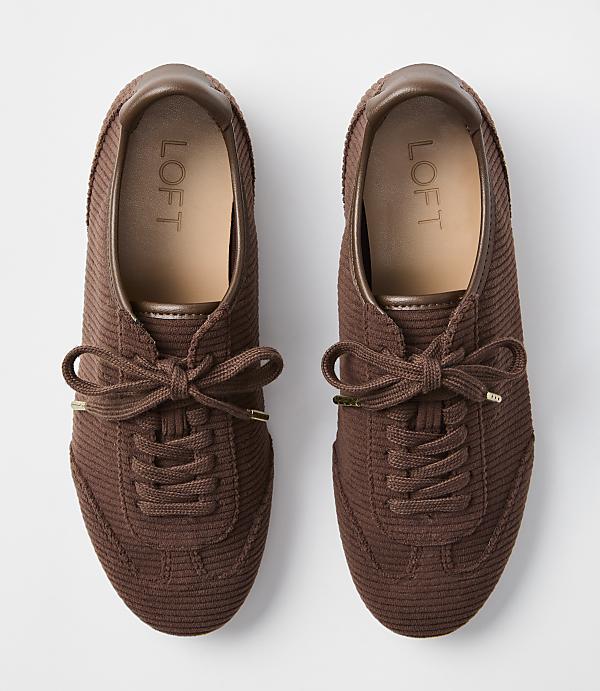 A pair of brown corduroy sneakers with tan insoles and brown laces are laid out on a plain white background.