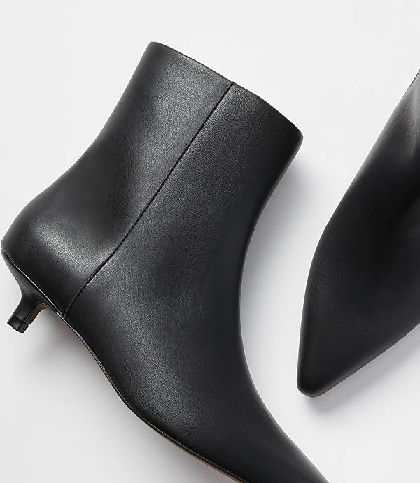 A pair of black leather kitten heel ankle boots are displayed against a plain white background.