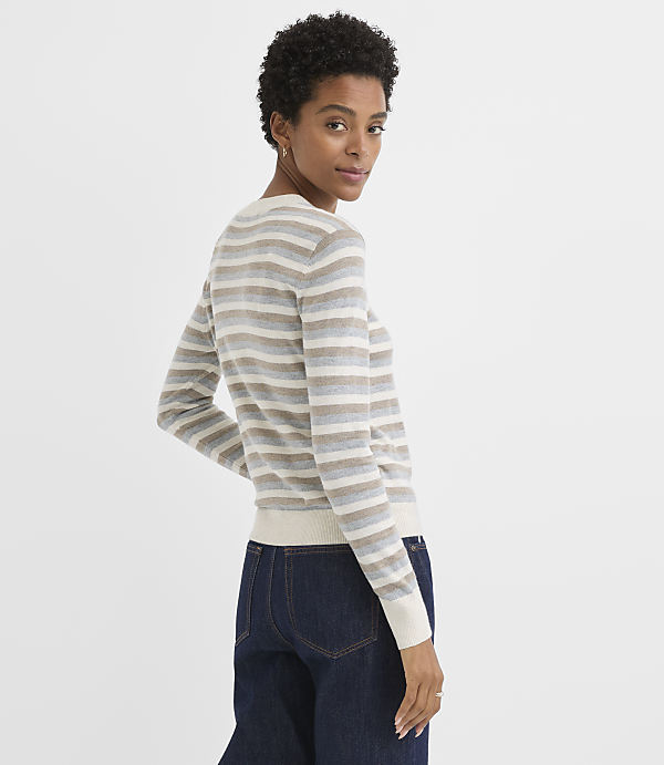 A woman in a striped sweater and jeans stands against a plain white background.