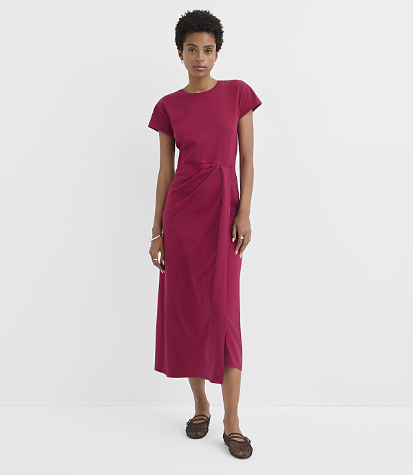 A woman in a magenta dress stands against a plain white background.