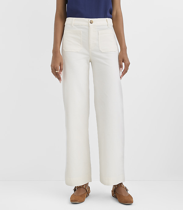 A person stands in white wide-leg pants and brown shoes against a plain white background.