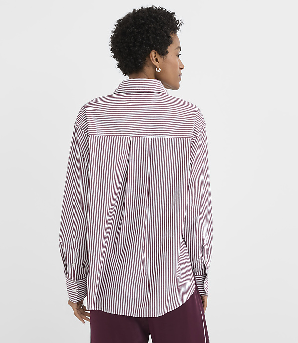 A woman in a striped shirt stands against a plain white background.