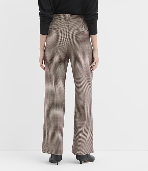 A person wearing brown plaid wide-leg pants and black shoes stands against a plain white background.