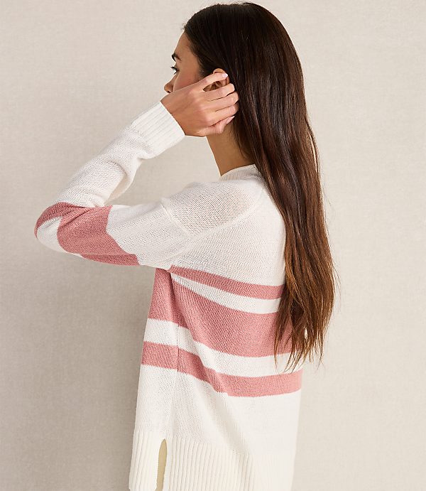 A woman in a striped sweater stands against a plain, light-colored background.