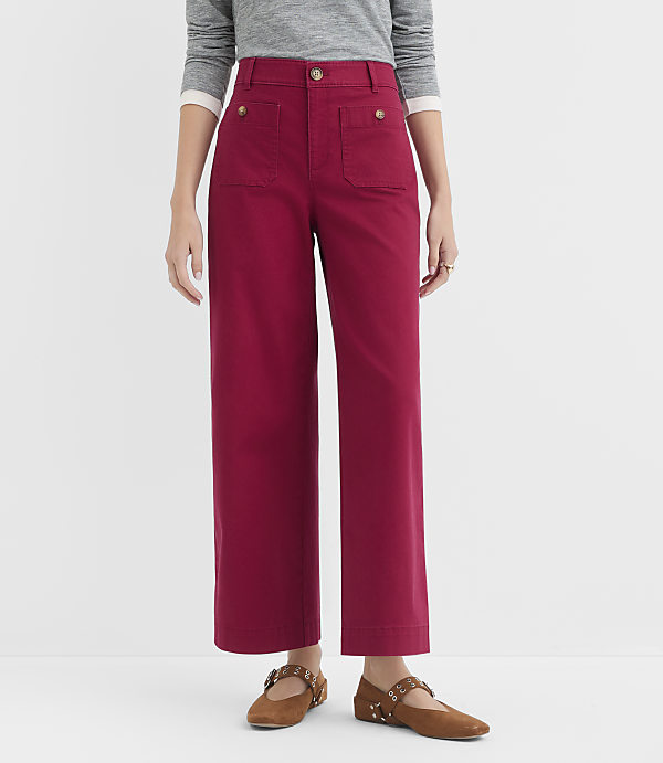 A person stands in front of a white background wearing red wide-leg pants and brown flats.