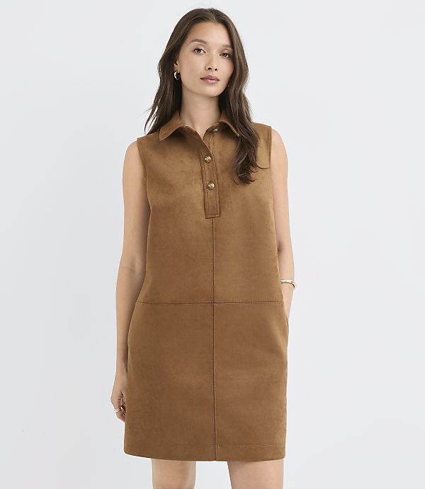 A woman in a brown suede shift dress stands against a plain white background.