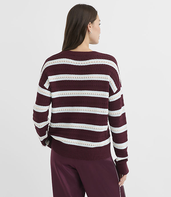 A woman in a maroon and white striped sweater stands against a plain white background.