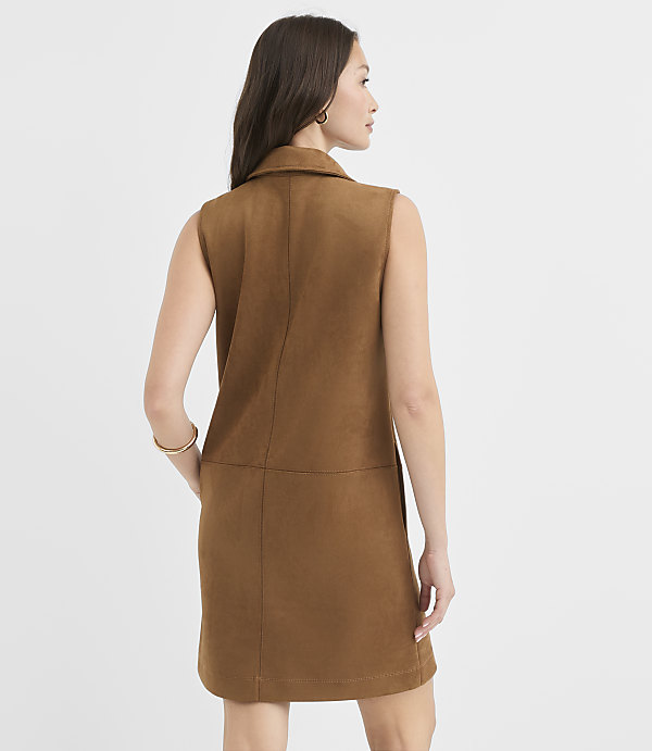 A woman in a brown sleeveless dress stands with her back to the camera against a plain white background.