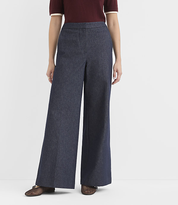 A person stands in wide-leg denim pants and a maroon top against a plain white background.