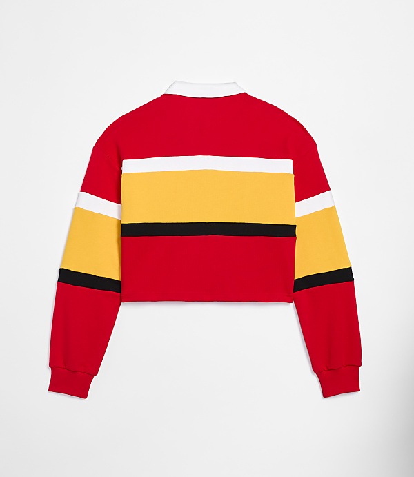 A red, yellow, and white striped cropped rugby shirt is displayed against a plain white background.