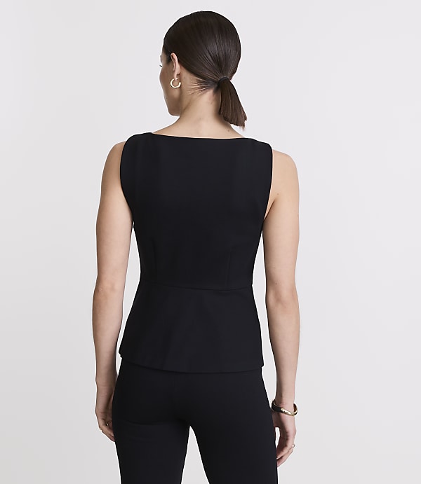 A woman in a black top and pants stands against a plain white background.