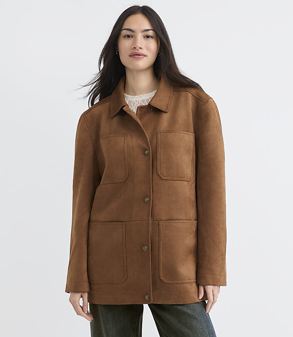 A woman in a brown suede jacket stands against a plain white background.
