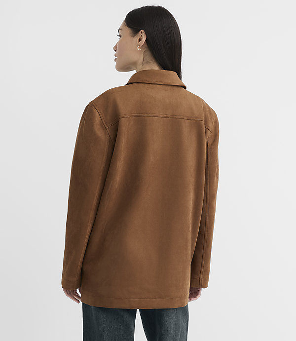 A woman in a brown suede jacket stands against a plain white background.