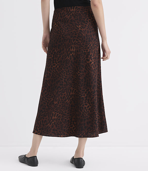 A person wearing a brown leopard-print skirt and black flats stands against a plain white background.