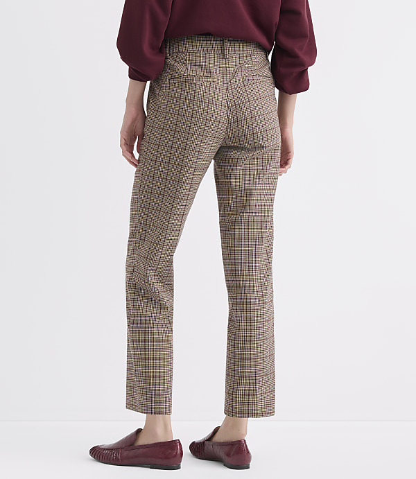 A person wearing plaid pants and burgundy loafers stands against a plain white background.