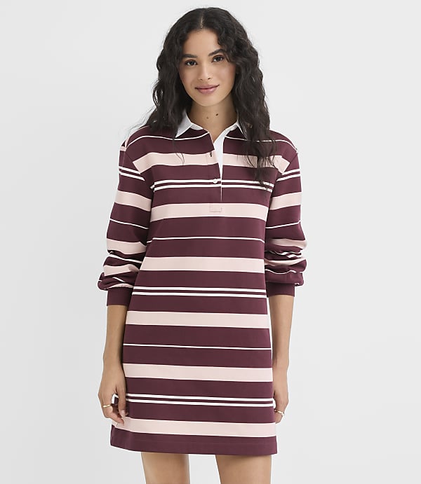 A woman in a striped rugby dress stands against a plain white background.