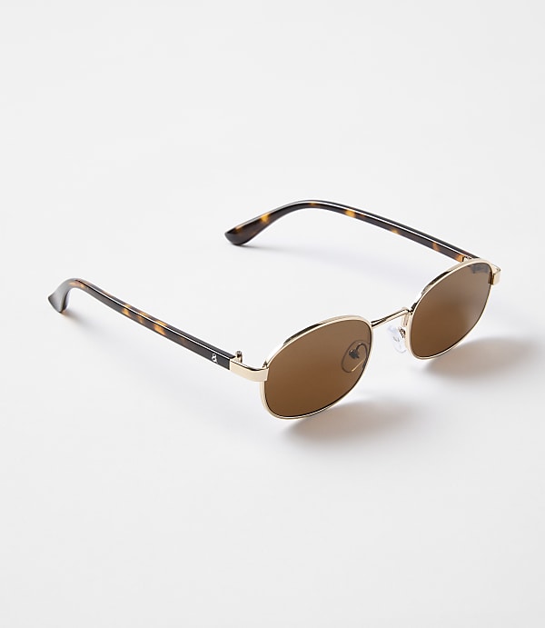 Tortoiseshell-patterned sunglasses with gold frames rest on a plain white background.