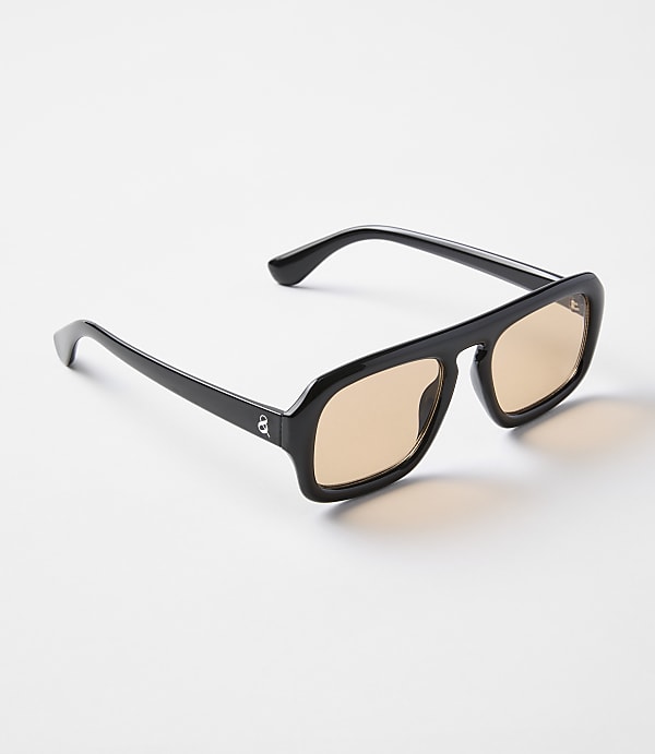 A pair of black-framed sunglasses with amber lenses rests on a plain white background.