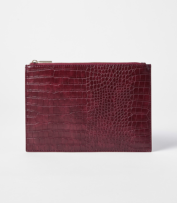 A deep red, crocodile-embossed clutch with a gold zipper rests on a plain white background.