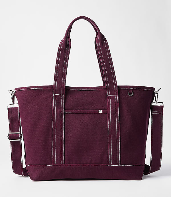 A maroon canvas tote bag with white stitching and a detachable shoulder strap sits against a plain white background.