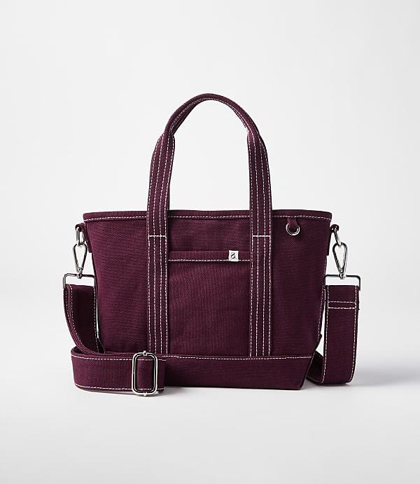 A burgundy canvas tote bag with white stitching and a detachable shoulder strap rests on a white background.