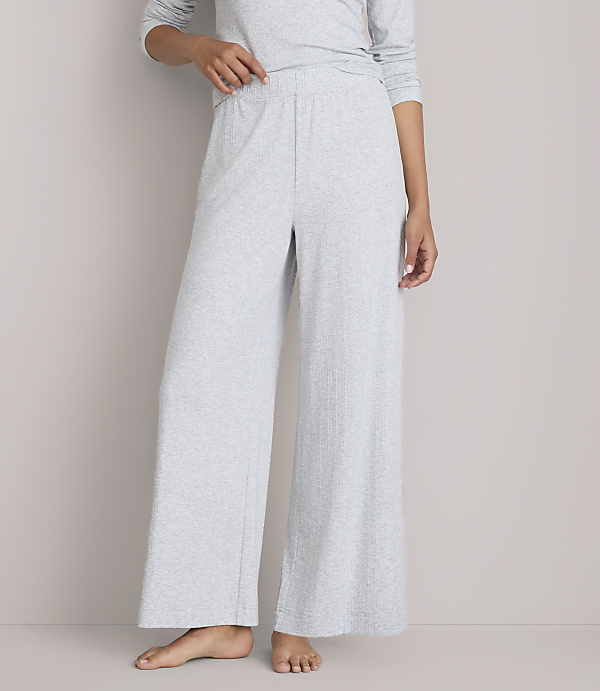 A person stands in light gray wide-leg pajamas against a plain gray background.