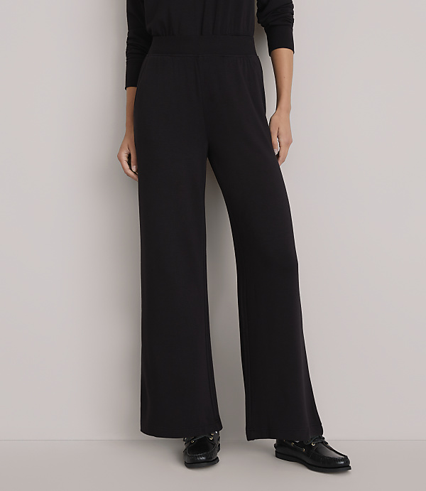 A person stands in wide-legged black pants and black shoes against a plain white background.