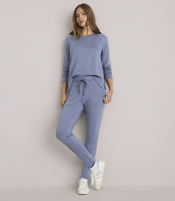 A woman in a blue loungewear set stands against a plain white background.