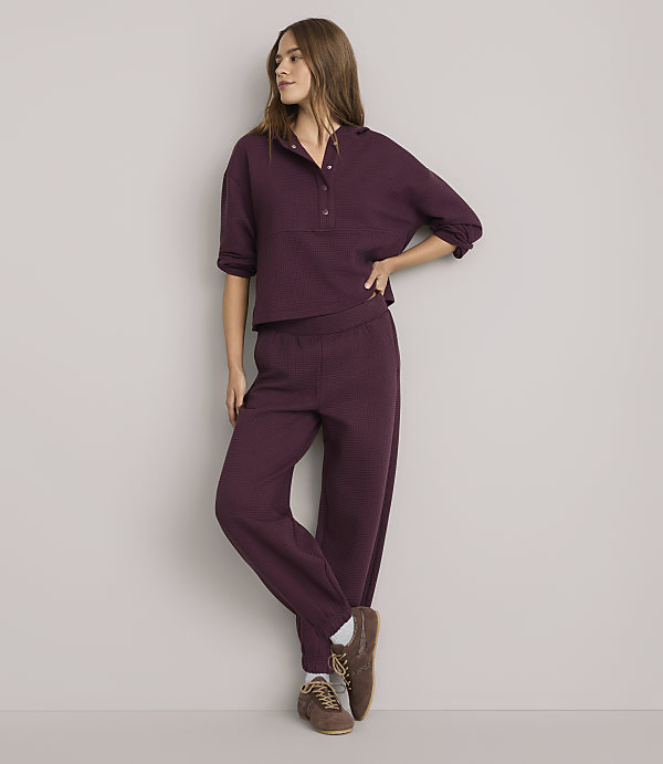A woman in a burgundy loungewear set stands against a plain white background.