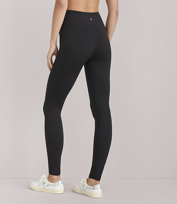 A person wearing black leggings and white sneakers stands against a plain white background.