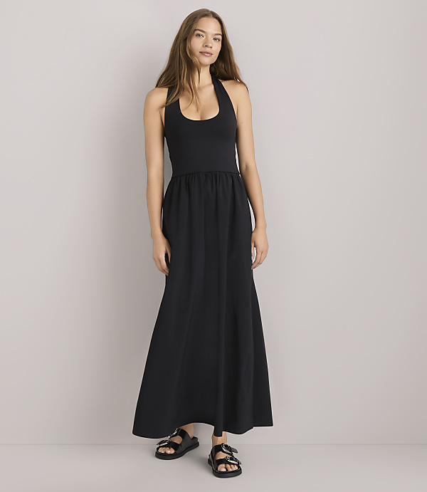 A woman in a black halter dress and a green striped shirt sits against a plain white background.