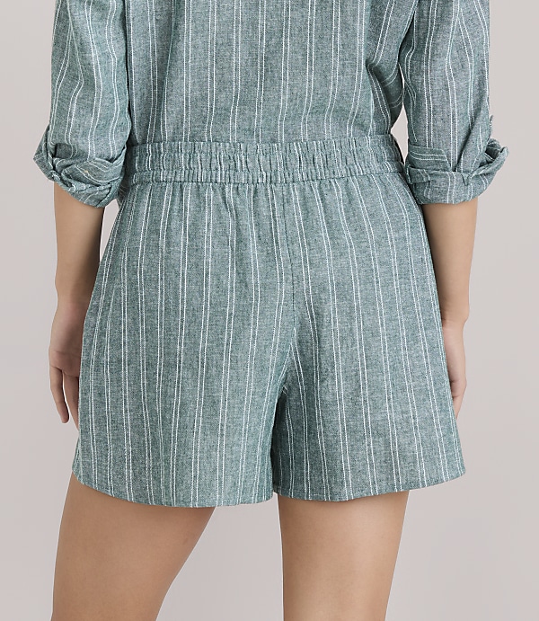 A person wearing a green and white striped romper is shown from the back, with a plain white background.