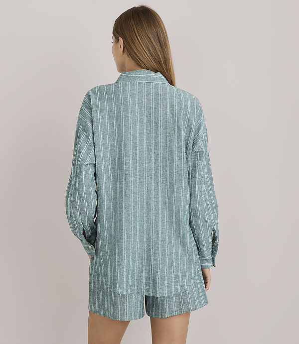 A woman in a striped pajama set stands against a plain white background.