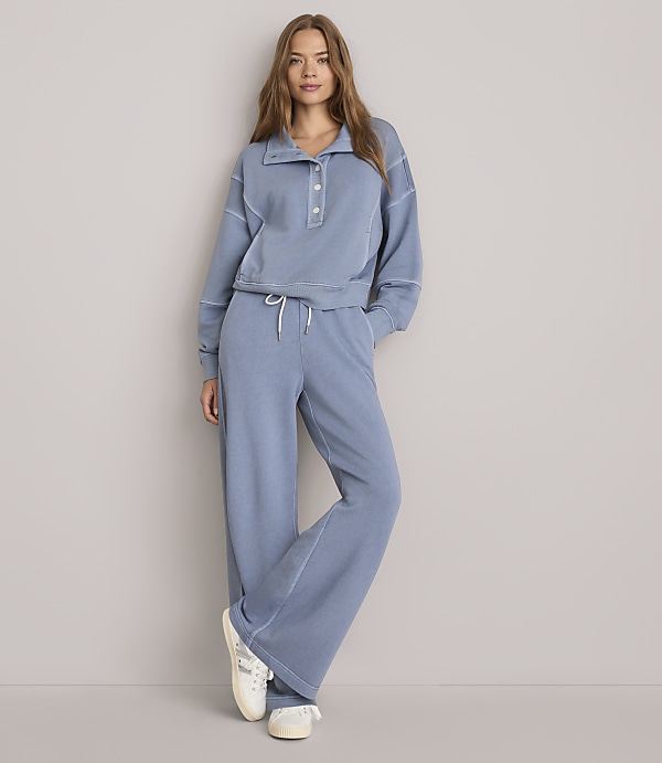 A woman in a blue loungewear set stands against a plain gray background.