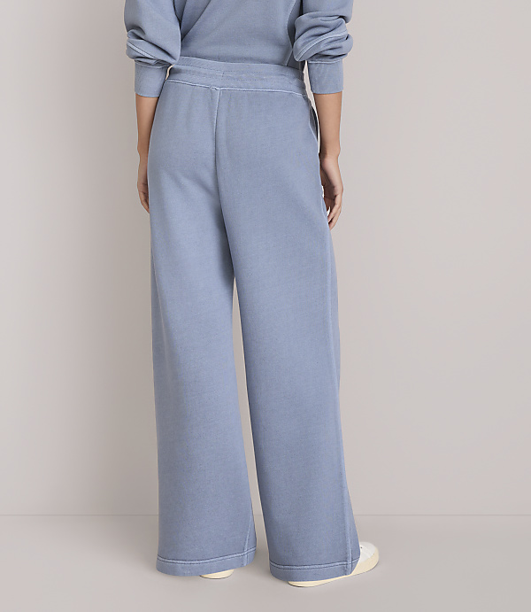 A person wearing light blue wide-leg sweatpants stands against a plain white background.