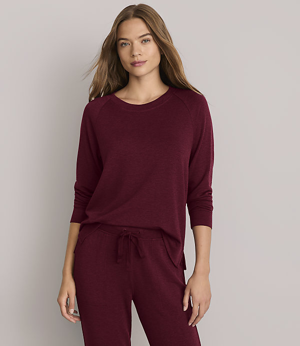 A woman in a burgundy loungewear set stands against a plain white background.