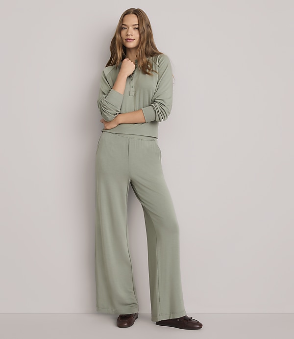 A young woman in a sage green loungewear set stands against a plain white background.