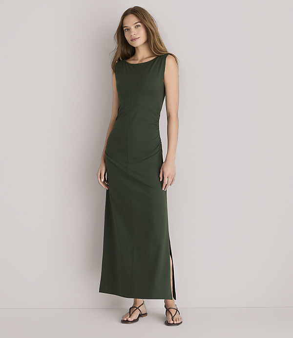 A woman in a dark green maxi dress stands against a plain white background.