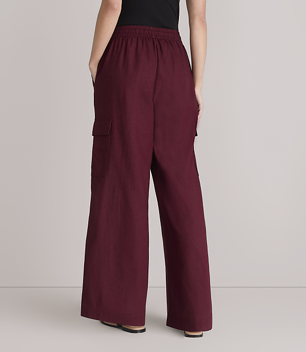 A person stands with their back to the camera, wearing maroon cargo pants and black shoes, against a plain white background.