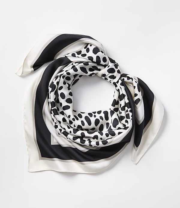 A black, white, and grey patterned silk scarf is neatly folded against a plain white background.