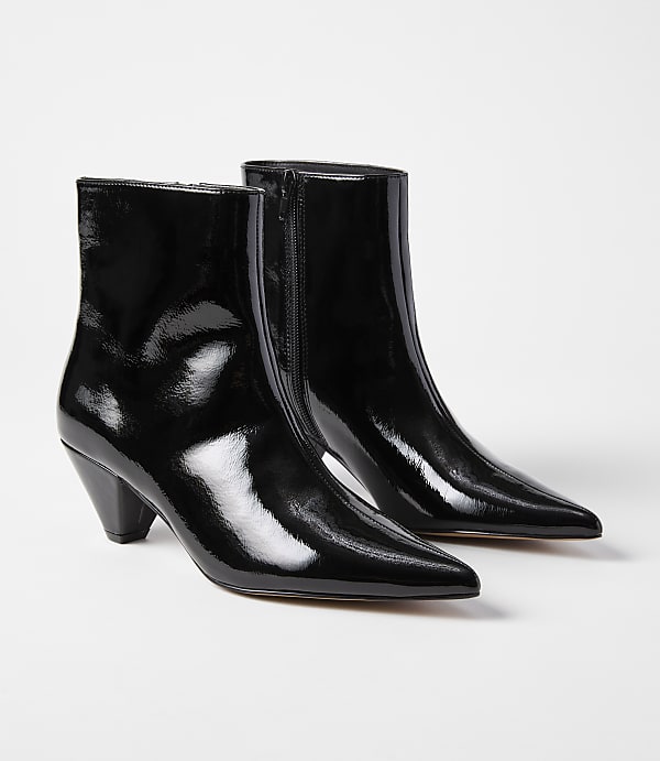 A pair of glossy black pointed-toe ankle boots with a kitten heel are displayed against a plain white background.