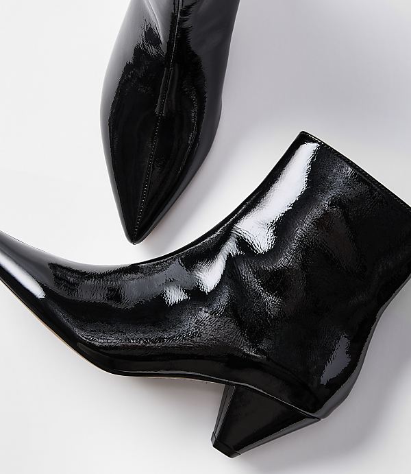 Two glossy black patent leather ankle boots with pointed toes and block heels rest on a plain white background.